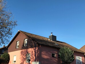 A building with a red facade, a tiled roof, and a chimney. - Private rental Ina - holiday room (Clausthal-Zellerfeld)
