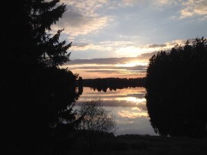 A natural landscape with a calm lake, surrounded by dense trees, and a clear sky. - Private rental Ina - holiday room (Clausthal-Zellerfeld)