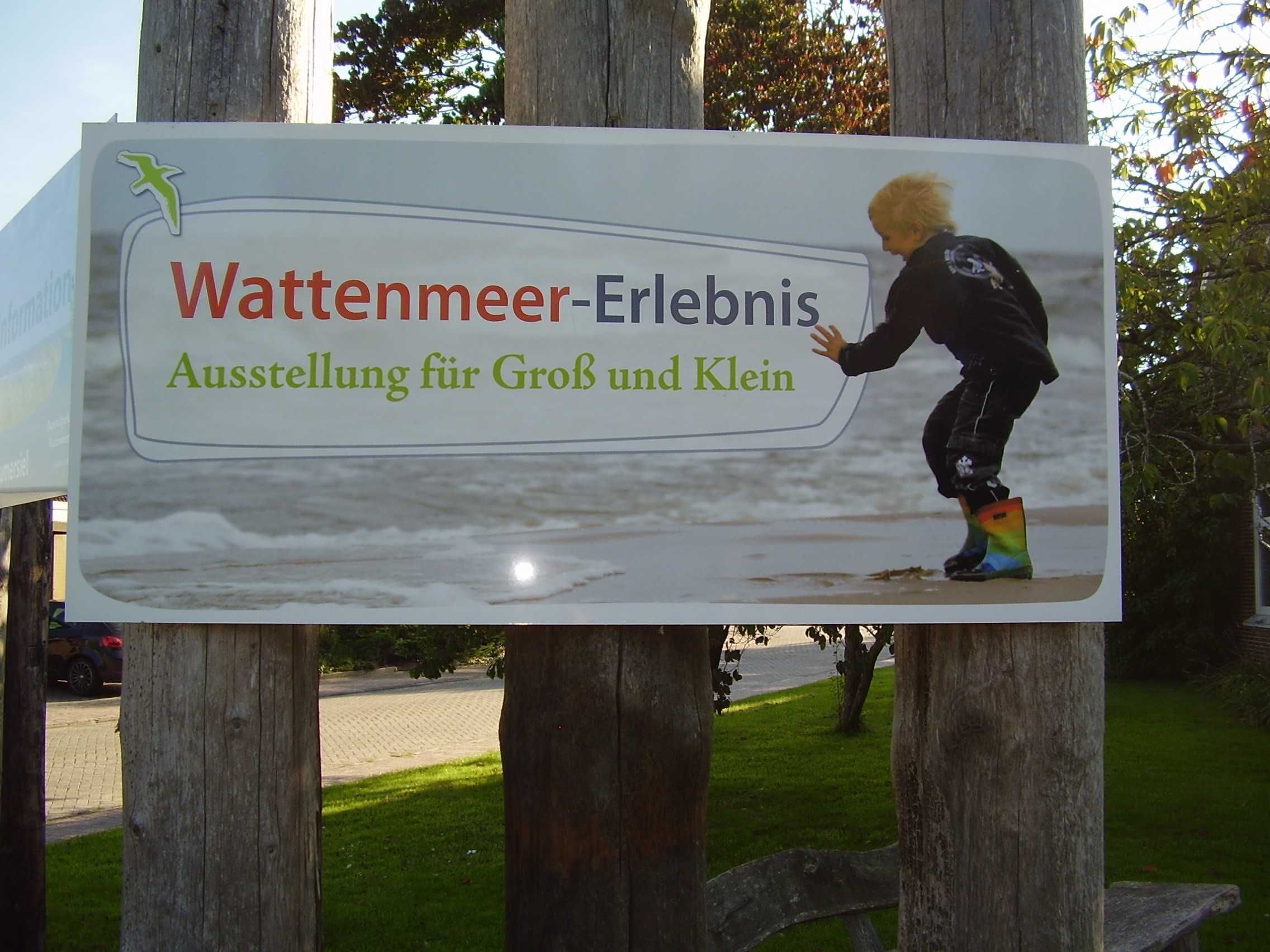 Un panneau d’affichage représentant un enfant jouant dans l’eau, intitulé « Wattenmeer-Erlebnis » et « Exposition pour petits et grands ».