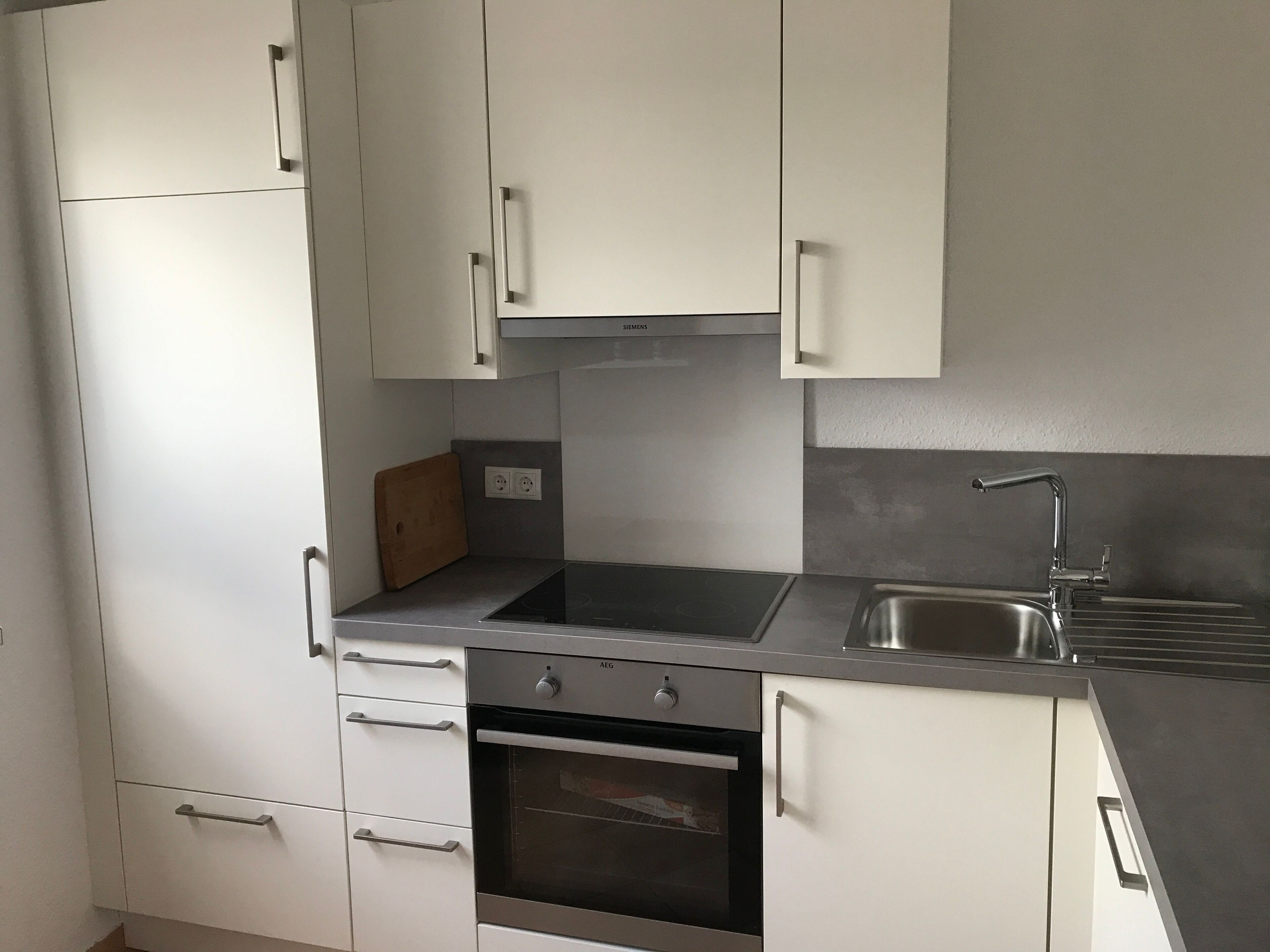 A modern kitchen with white cabinets, a stainless steel sink, and an oven.