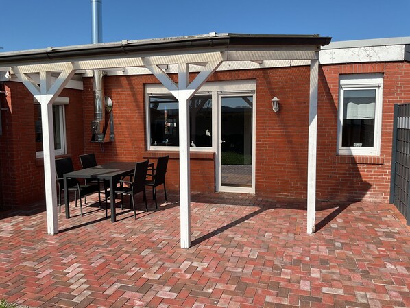 A patio with a brick floor, a table, and chairs.