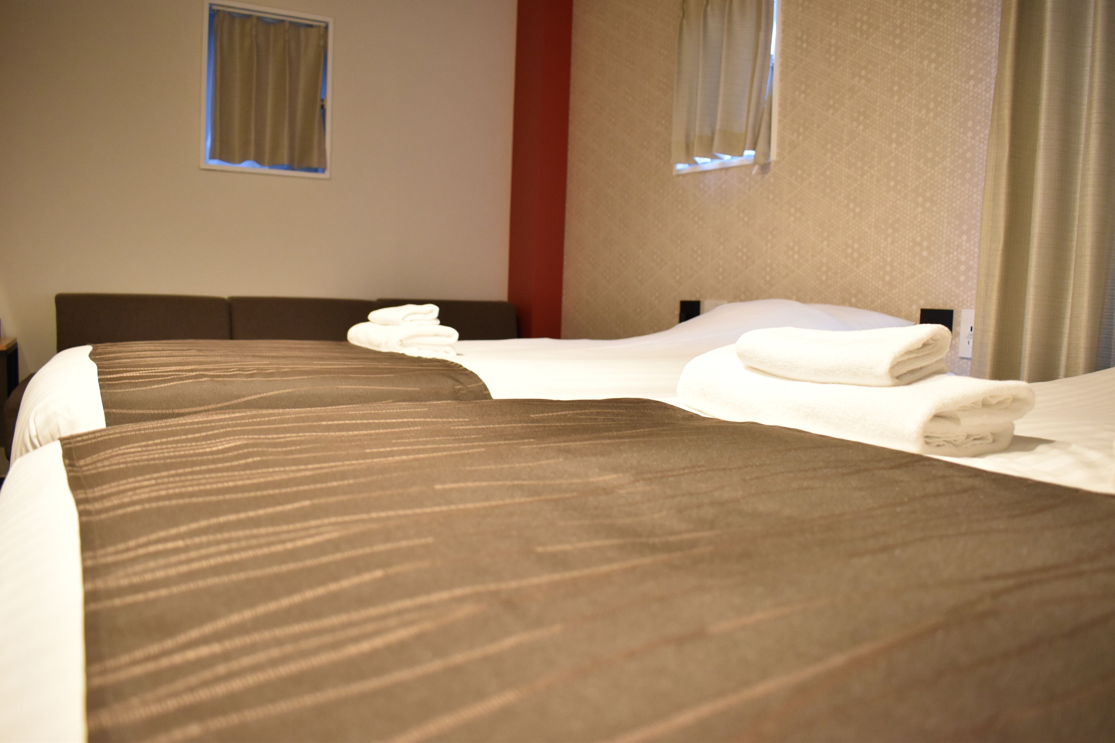 Ett hotellrum med en stor säng, två kuddar och prydligt hopvikta handdukar.