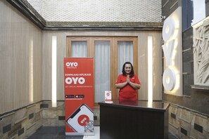 A hotel reception area with a large OYO Hotels sign, a digital screen, and a marble wall.