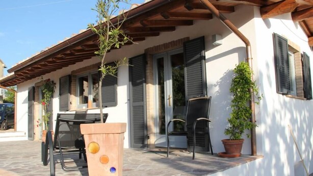 A house with a patio, a table, chairs, and potted plants. - Eco house with pool and fantastic views (Scansano)
