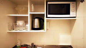 Une cuisine de taille réduite, équipée d’un évier, d’une cuisinière et d’un four à micro-ondes.