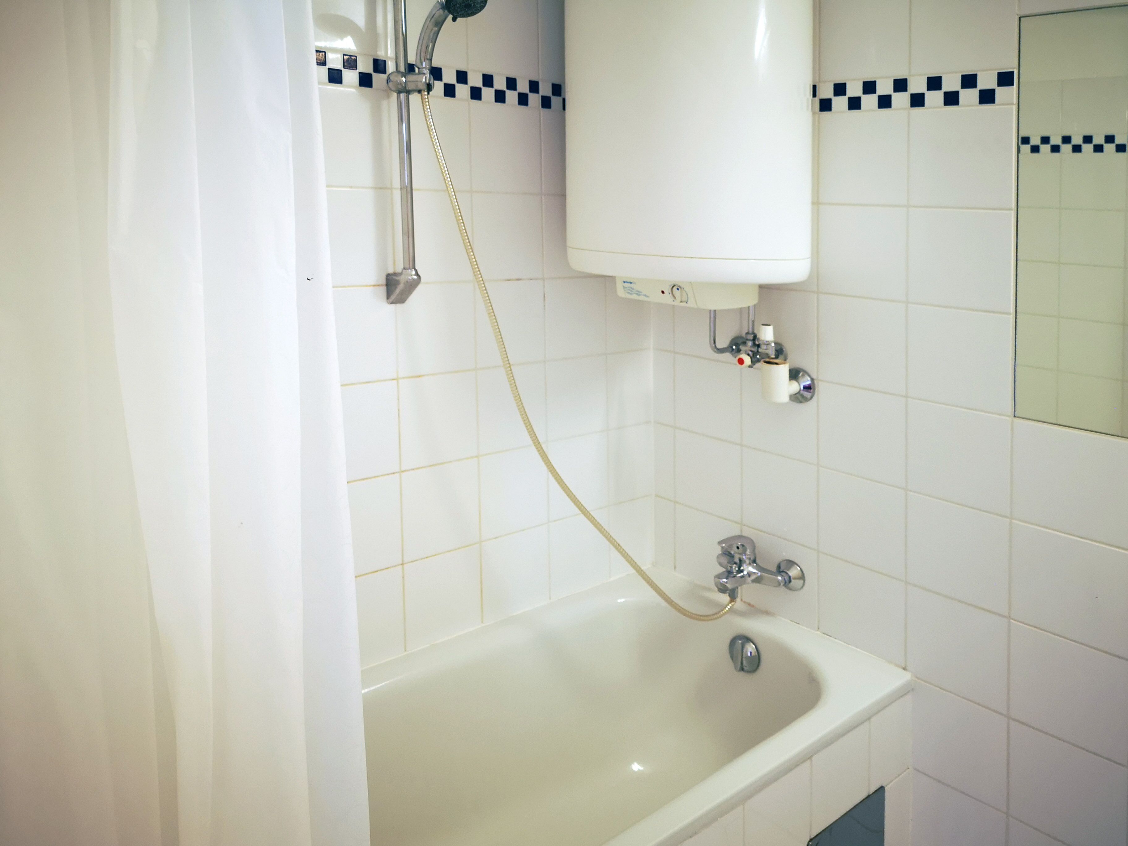 Et badeværelse med badekar, brusehoved og toilet.