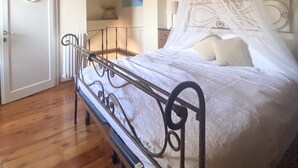 A bedroom with a bed under a canopy, wooden beams on the ceiling, and a white door. - UNIQUE LARGE TERRACE WITH VIEWS TO CHAINTI VALLEY AND DRINK (Ruffoli)