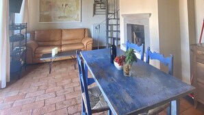 A rustic dining area with a wooden table, blue chairs, a brick floor, a sofa, and a fireplace. - UNIQUE LARGE TERRACE WITH VIEWS TO CHAINTI VALLEY AND DRINK (Ruffoli)