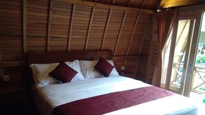 A wooden-framed room with a bed, white bedding, and two red pillows. - Visual Inn (Penida Island)
