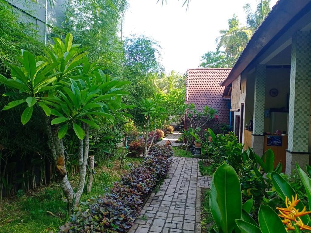 Un chemin de jardin menant à un bâtiment dont le toit est recouvert de tuiles.