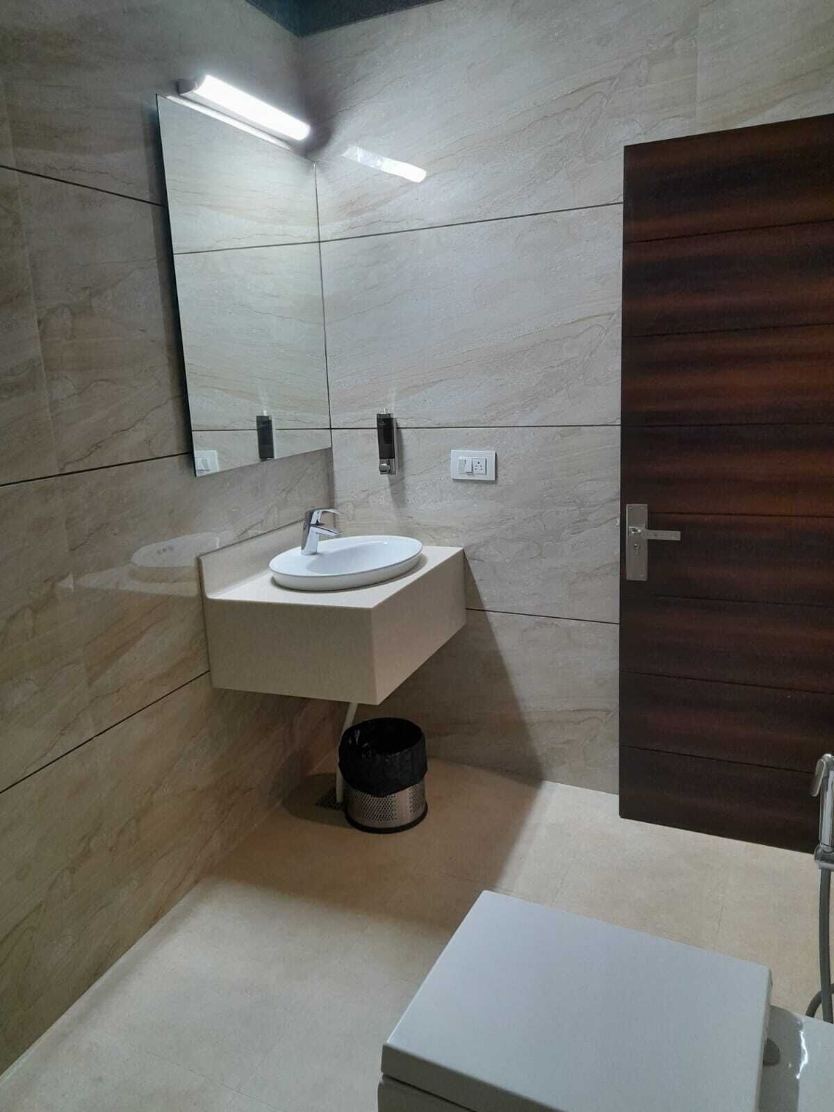 A modern bathroom with a white sink, mirror, and a wooden door.