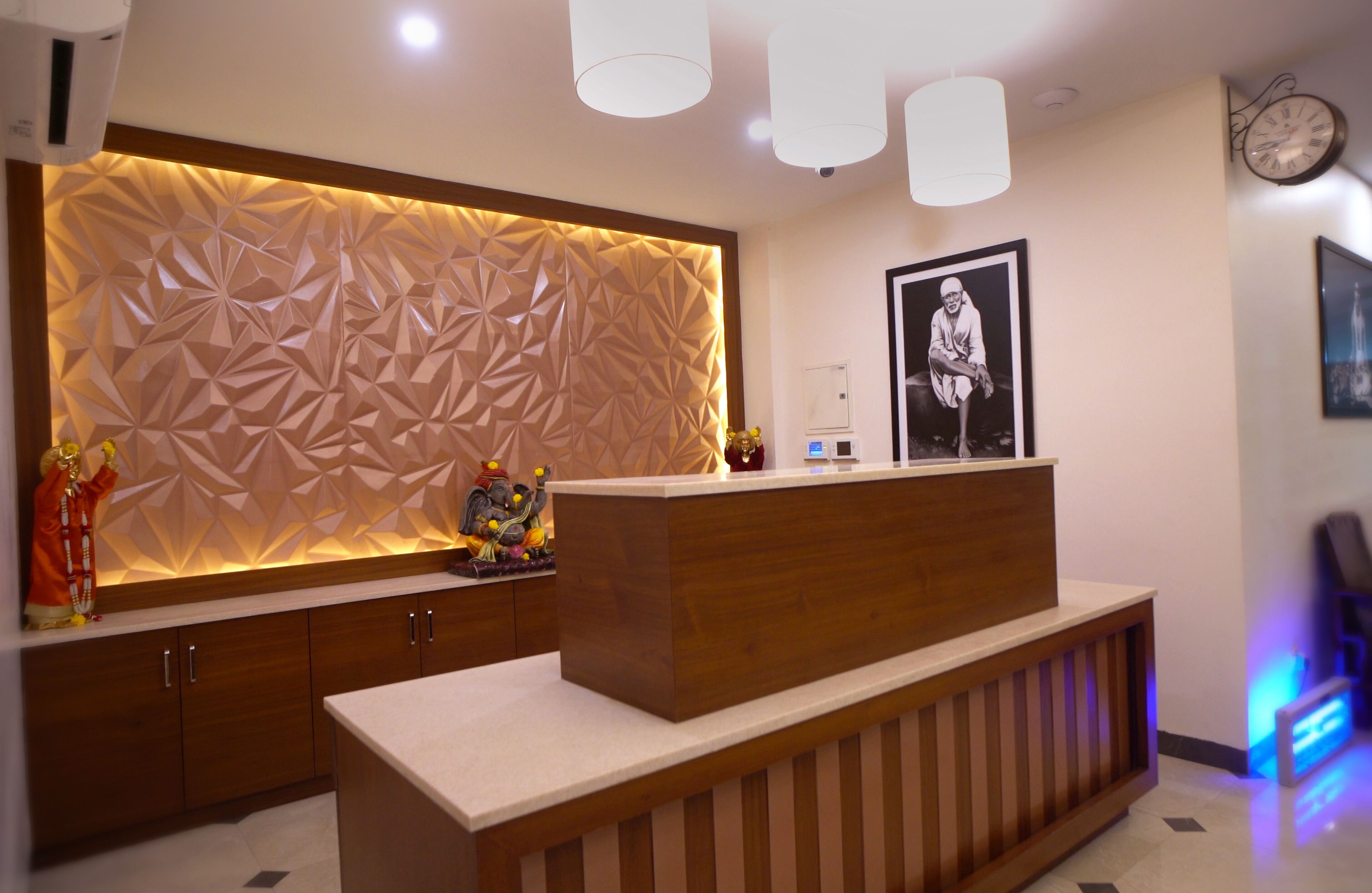 A reception area with a modern design, featuring a geometric patterned wall, a wooden reception desk, and a clock on the wall.