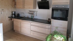 A modern kitchen with wooden cabinets, a built-in oven, and a coffee maker.