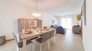 A modern kitchen with a dining table, chairs, and a hanging light fixture.
