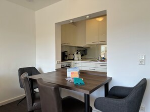 Un espace repas avec une table, des chaises et une cuisine en arrière-plan.