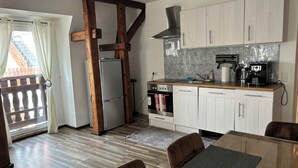 Eine moderne Küche mit Holzbalken, einem Edelstahlkühlschrank, einem Einbauofen und einer Kaffeemaschine.
