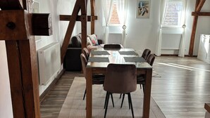 Ein Essbereich mit einem Holztisch und Stühlen, einem weißen Heizkörper und einem Fenster mit Vorhängen.