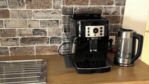 Eine Küche mit Steinrückwand, einer Kaffeemaschine und einem Wasserkocher auf der Arbeitsfläche.