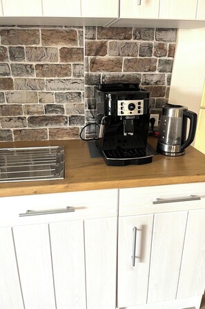 Enjoy cooking in this well-equipped kitchen with a coffee maker, coffee pot, and wooden cutting board.