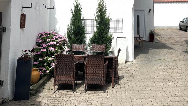 Ein traditionelles Fachwerkhäuschen mit einem kleinen Balkon, einem Essbereich mit Korbmöbeln und einem Blumentopf.