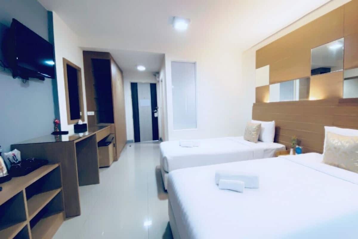 Una habitación de hotel con dos camas, televisión, escritorio y espejo.