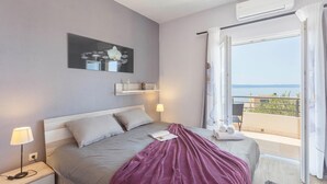 Een slaapkamer met een bed, bedlampen, een schilderij, een raam met uitzicht en een balkon.