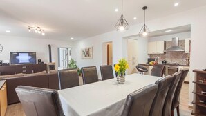 Een moderne eetruimte met een witte tafel, bruine lederen stoelen en twee hanglampen.