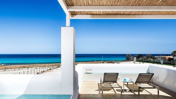 A balcony with two lounge chairs, a small table, and a view of the ocean. - Lavanda - Front Sea Villa for 8 People with Pool (Reitani)