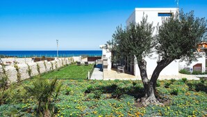 A modern building with a white facade, a stone pathway, and a tree in the foreground. - Lavanda - Front Sea Villa for 8 People with Pool (Reitani)