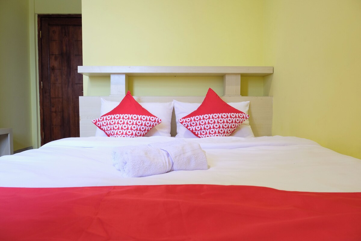 Ein Bett mit weißroter Bettdecke, zwei Kissen mit rotem und weißem Muster und ein weißes Kopfteil.