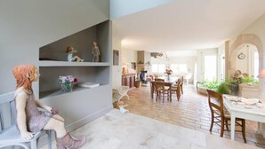 Amplia sala de estar con una mesa de comedor, sillas y una cocina al fondo.
