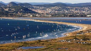 Un pueblo costero con playa y práctica de windsurf.