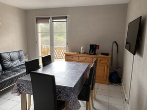 Une cuisine compacte comprenant une table à manger, des chaises, une machine à café et un aspirateur.