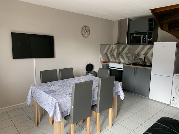 Una cucina compatta con zona pranzo, televisione a schermo piatto e forno a microonde.