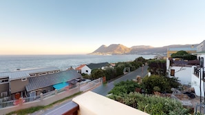 A coastal residential area with houses, a street, and a view of the ocean and mountains. - Whalesong Glencairn (Cape Town)