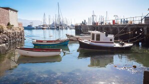 A marina with several boats docked, a stone wall, and a pier with steps leading to a higher platform. - Whalesong Glencairn (Cape Town)