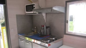 Pieni, käytännöllinen keittiönurkkaus, jossa on mikroaaltouuni, kahvinkeitin ja pesuallas.