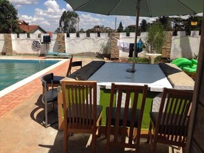 Una piscina al aire libre, sombrillas, sillones reclinables de piscina