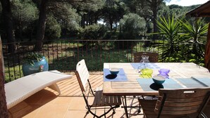An outdoor patio with a wooden table, chairs, and a view of a forested area. - House 150 meters from the beach PALOMBAGGIA private access (PORTO VECCHIO)