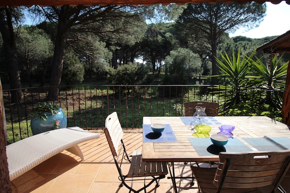 An outdoor patio with a wooden table, chairs, and a view of a forested area. - House 150 meters from the beach PALOMBAGGIA private access (PORTO VECCHIO)