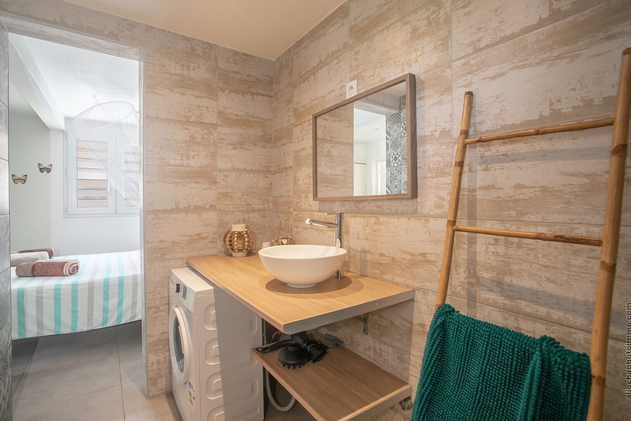 Un baño pequeño con tocador de madera, un espejo grande y una lavadora.