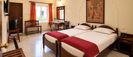 A hotel room with a bed, a desk, a chair, a television, and a painting on the wall.