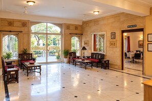 Un hall d’hôtel comprenant une salle de réunion, des meubles en bois et de grandes fenêtres.