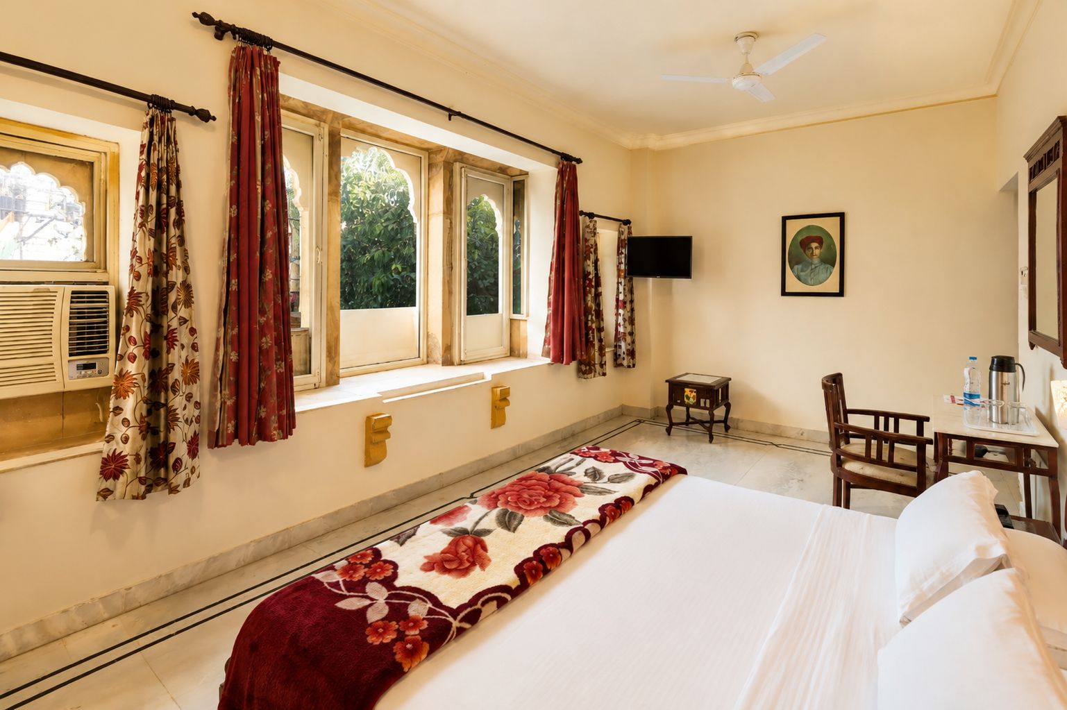 Una habitación de hotel con una cama, un escritorio con silla, un televisor y una ventana con cortinas.