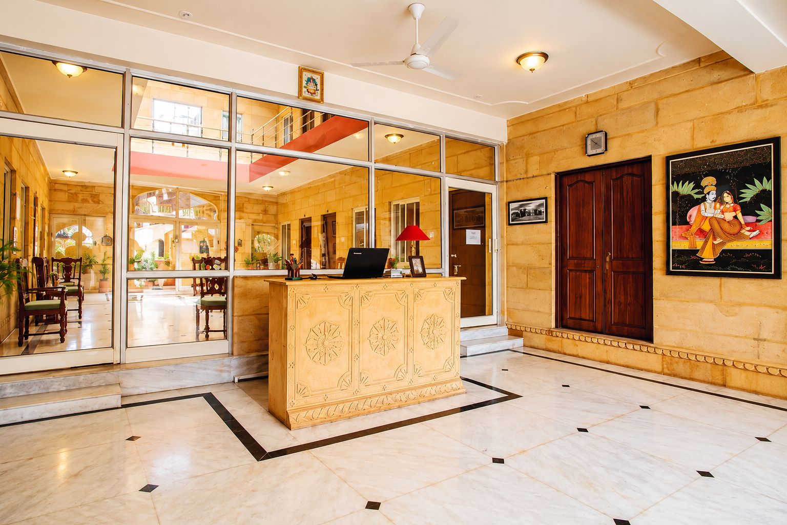 A hotel lobby with a reception desk, a staircase, and a large window.