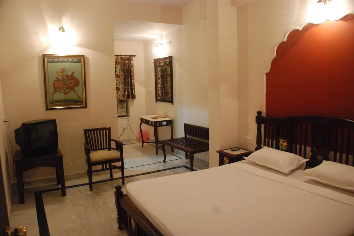 A bedroom with a bed, a chair, a small table, and a television.