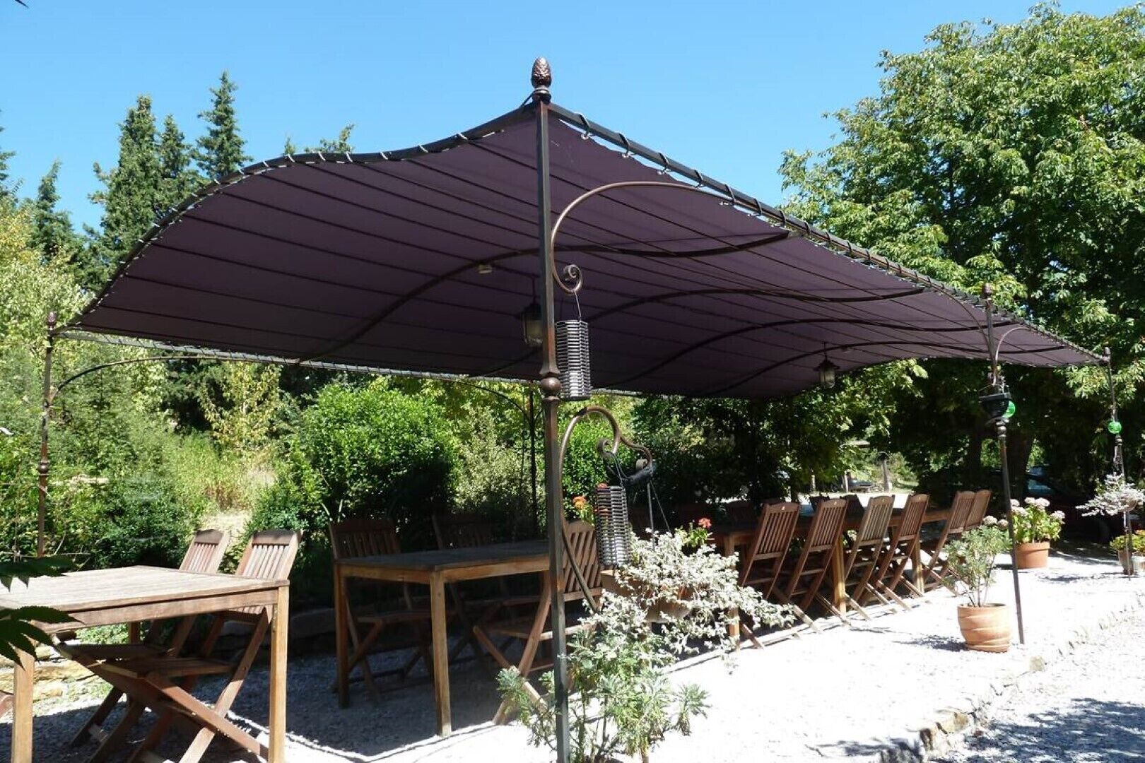 An outdoor patio with a large umbrella, wooden tables, and chairs.