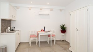 A compact kitchen with white cabinetry, a dining table with chairs, a small side table, and a potted plant. - Dubrovnik old city Studio apartment (Dubrovnik)