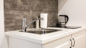 A kitchen with a stainless steel sink, a white countertop, and a brick backsplash. - Dubrovnik old city Studio apartment (Dubrovnik)