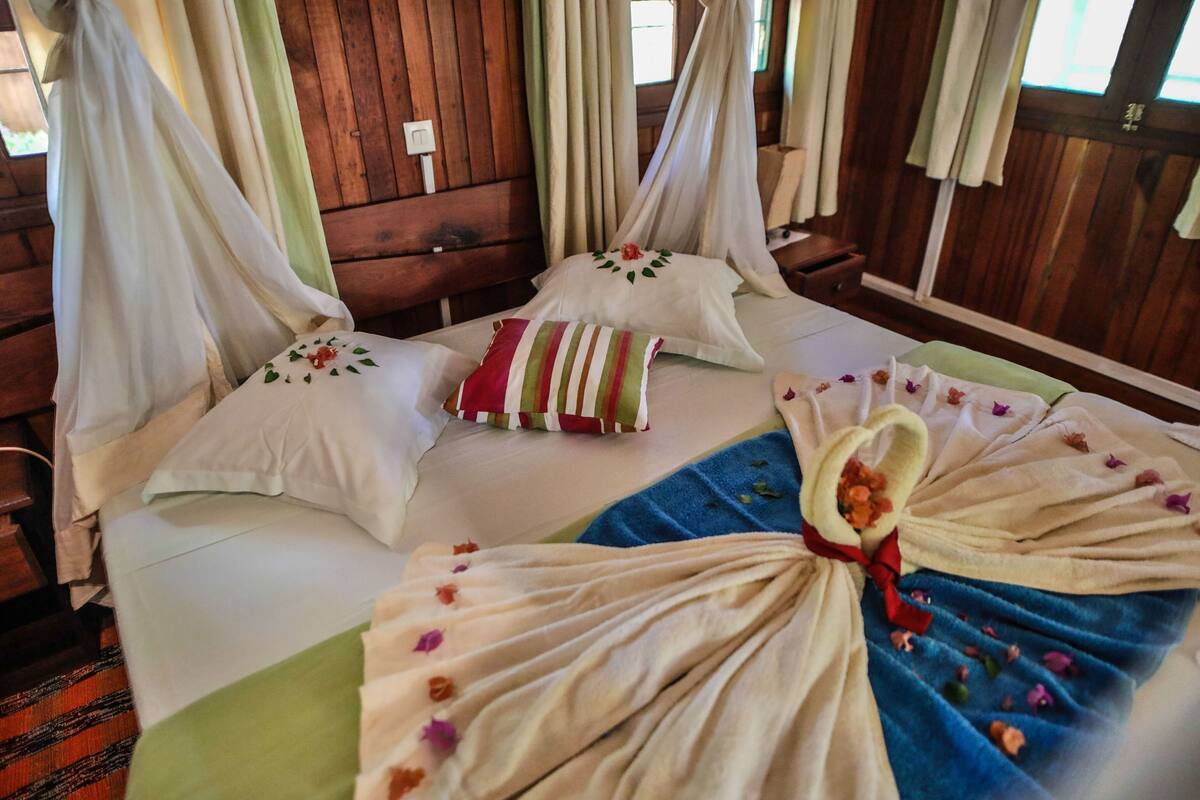 Ein Zimmer mit Bett, Baldachin und einem Vorhangfenster.